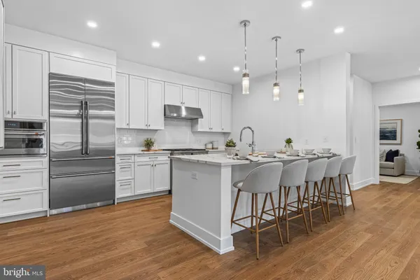 a kitchen with stainless steel appliances kitchen island granite countertop a table chairs and a sink