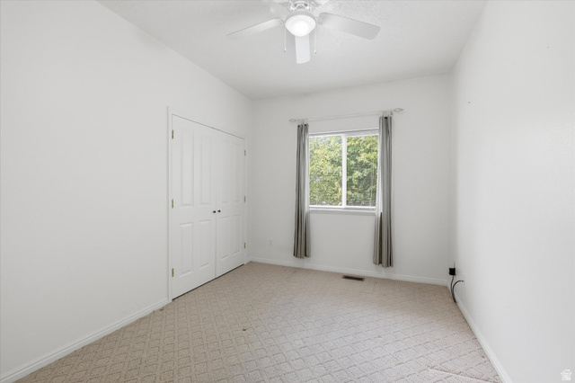 560 East 700 North Logan, UT 84321 - Photo 12 of 32 White-painted room featuring light-colored patterned carpet, a ceiling fan with light, and a double-door closet
