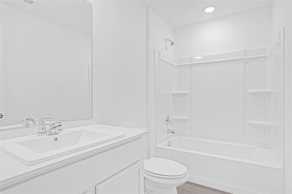 1033 Raintree Road Princeton, TX 75407 - Photo 21 of 26 a bathroom with a bathtub shower sink vanity and toilet