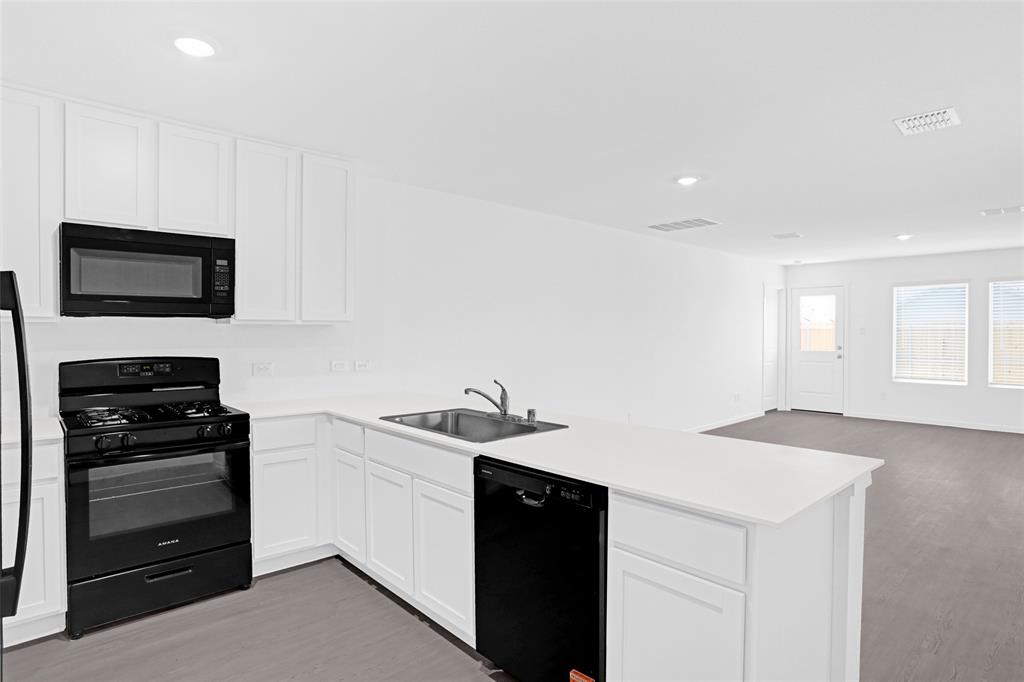 1033 Raintree Road Princeton, TX 75407 - Photo 5 of 25 a kitchen with a sink and a stove top oven with wooden floor