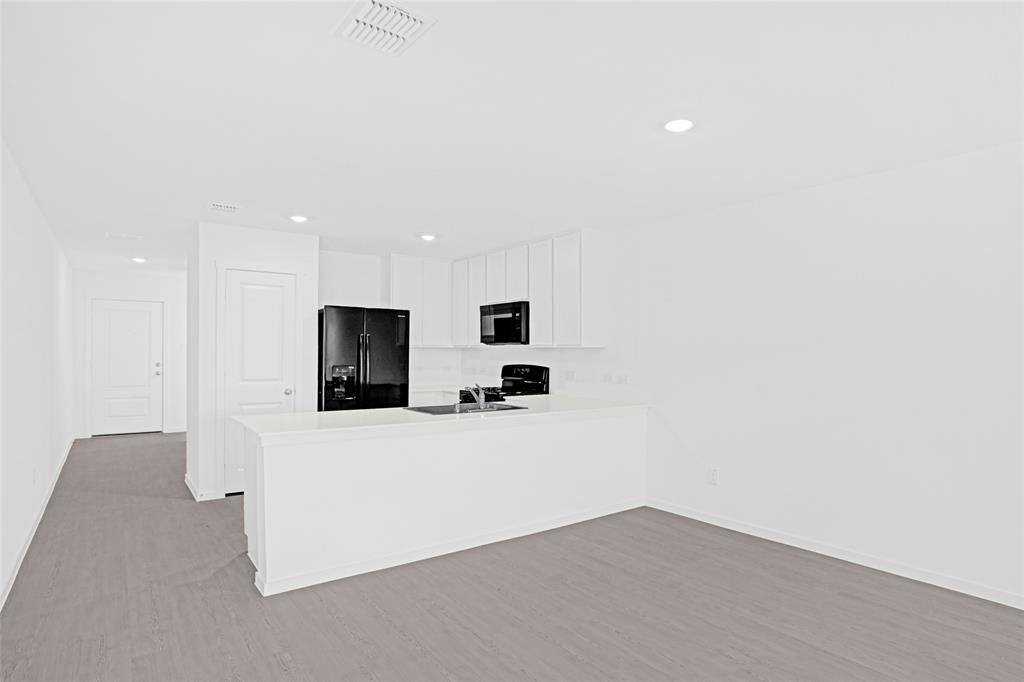 1033 Raintree Road Princeton, TX 75407 - Photo 9 of 25 a view of a kitchen with flat screen tv and refrigerator