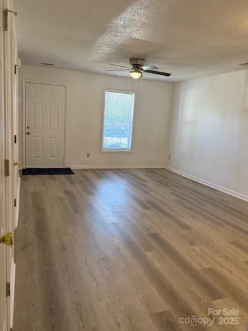 an empty room with wooden floor cabinet and windows