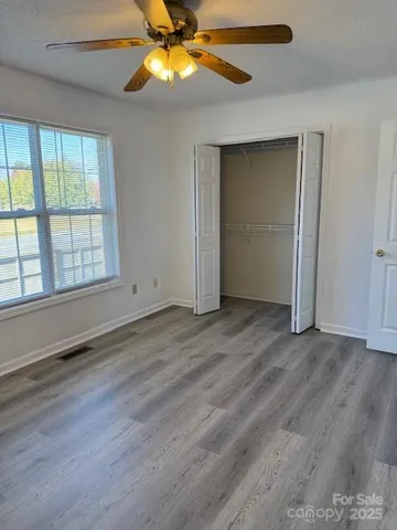 an empty room with wooden floor fan and windows