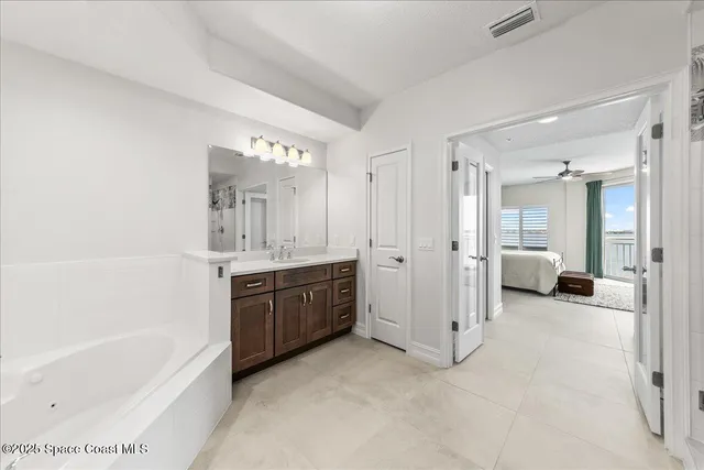 a spacious bathroom with a tub double sink and mirror