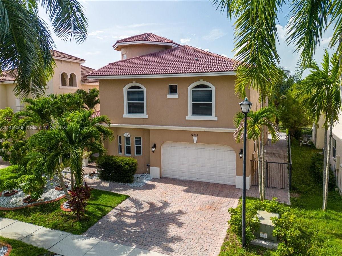 12441 Southwest 1st Street Plantation, FL 33325 - Photo 2 of 37 a front view of a house with a yard and a garage