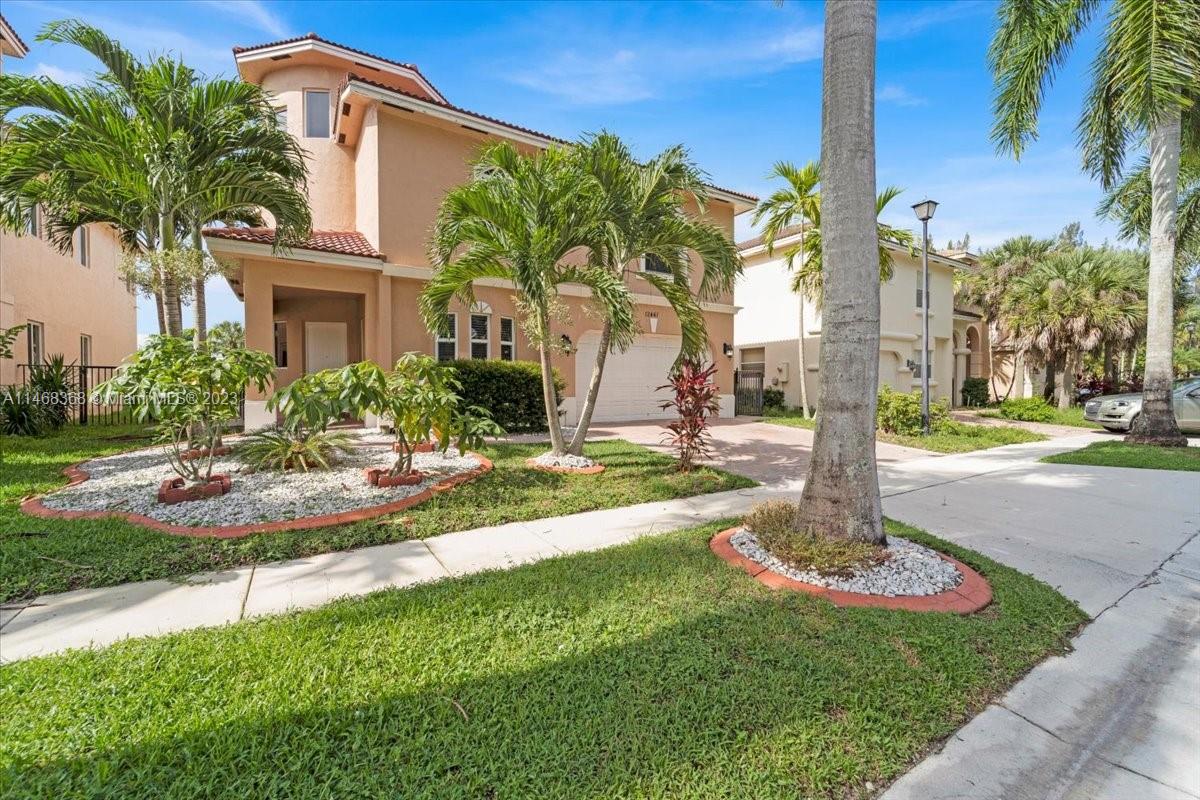 12441 Southwest 1st Street Plantation, FL 33325 - Photo 4 of 37 a front view of a house with garden and trees