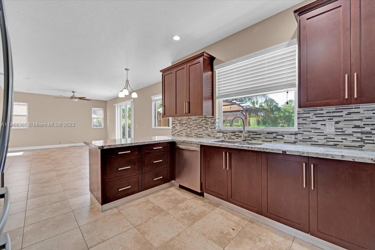 12441 Southwest 1st Street Plantation, FL 33325 - Photo 5 of 37 a large kitchen with granite countertop wooden cabinets and a sink