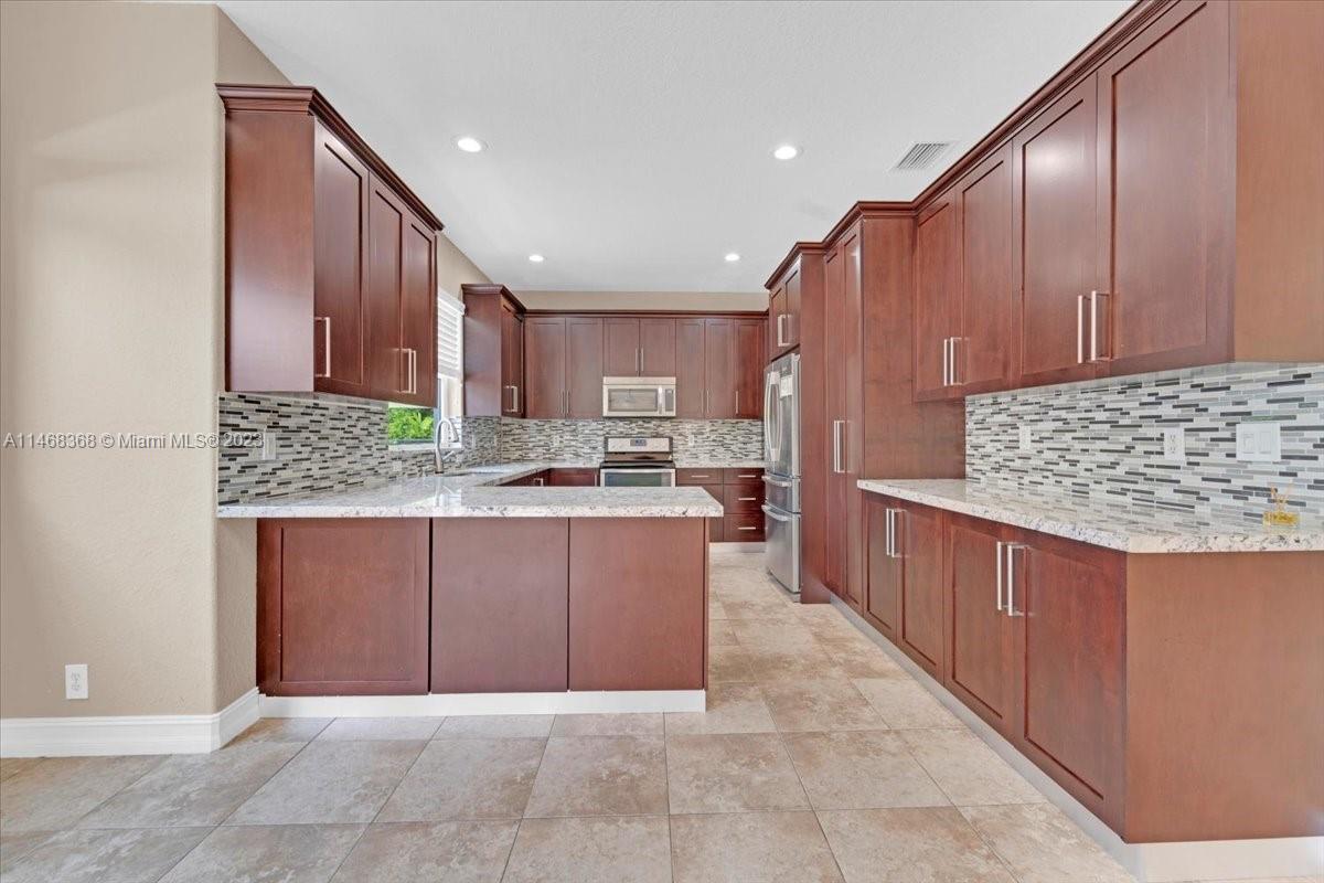 12441 Southwest 1st Street Plantation, FL 33325 - Photo 6 of 37 a kitchen with stainless steel appliances granite countertop a stove refrigerator sink and cabinets