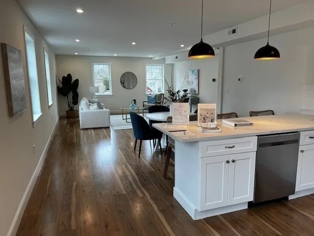 a kitchen with a sink dishwasher a dining table and chairs with wooden floor