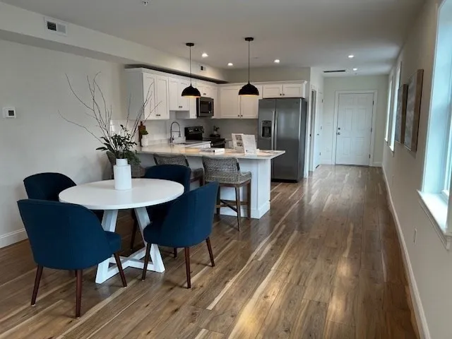 a kitchen with kitchen island a dining table chairs stainless steel appliances and cabinets