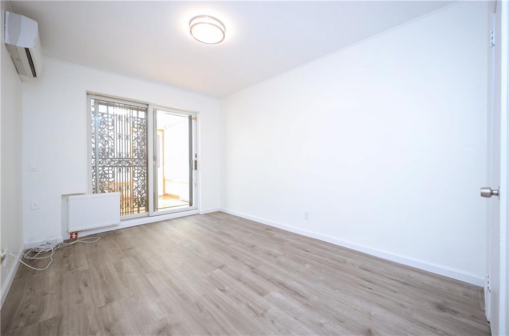 1940 20th Drive Brooklyn, NY 11214 - Photo 11 of 21 an empty room with wooden floor and windows