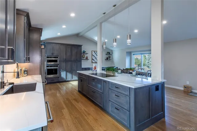a large kitchen with stainless steel appliances kitchen island granite countertop a large counter top and wooden floors