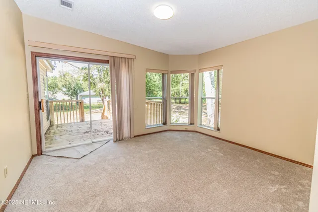 an empty room with a chandelier fan and windows