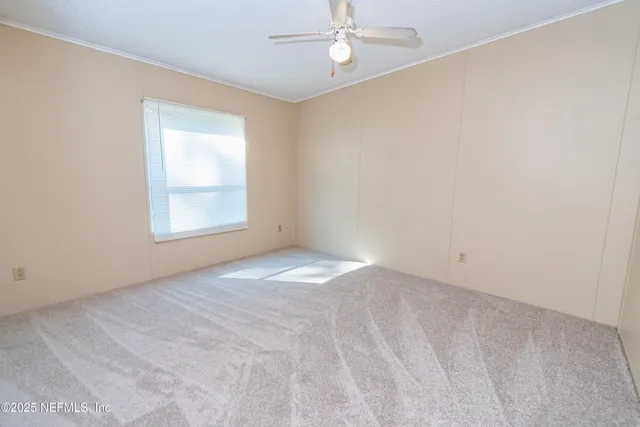 an empty room with a window and a fan