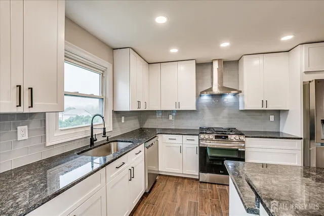 a kitchen with a sink wooden floor and stainless steel appliances