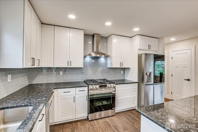 a kitchen with stainless steel appliances granite countertop a refrigerator and a stove top oven