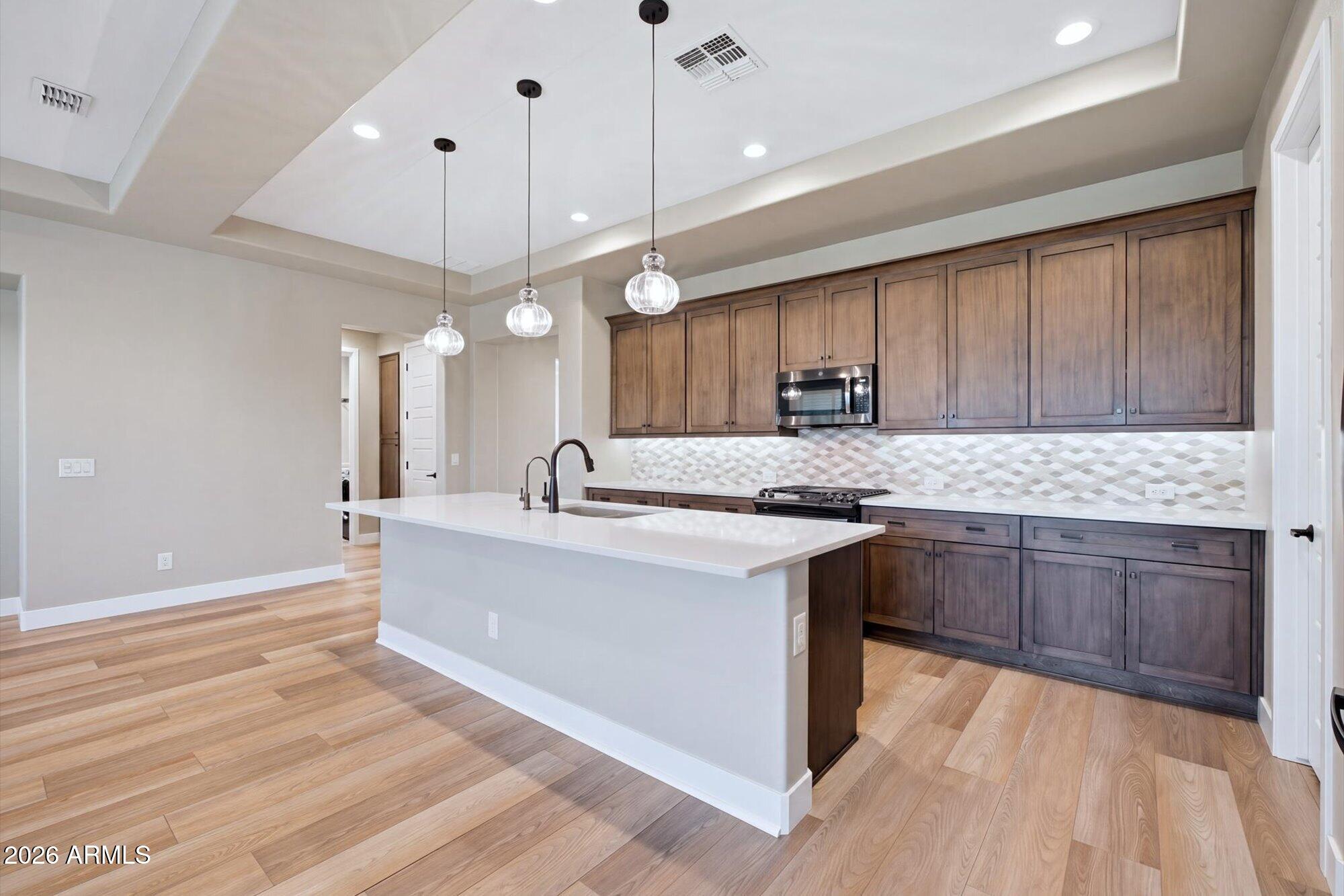16849 West Merrell Street Goodyear, AZ 85395 - Photo 11 of 35 a kitchen with granite countertop a sink cabinets and wooden floor