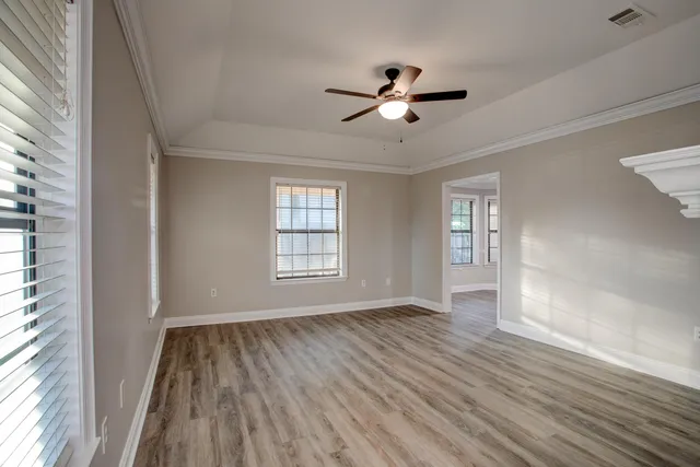 a view of an empty room with wooden floor and a window