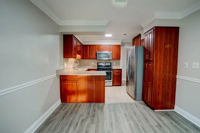 a kitchen with stainless steel appliances granite countertop a refrigerator a sink dishwasher and wooden cabinets with wooden floor