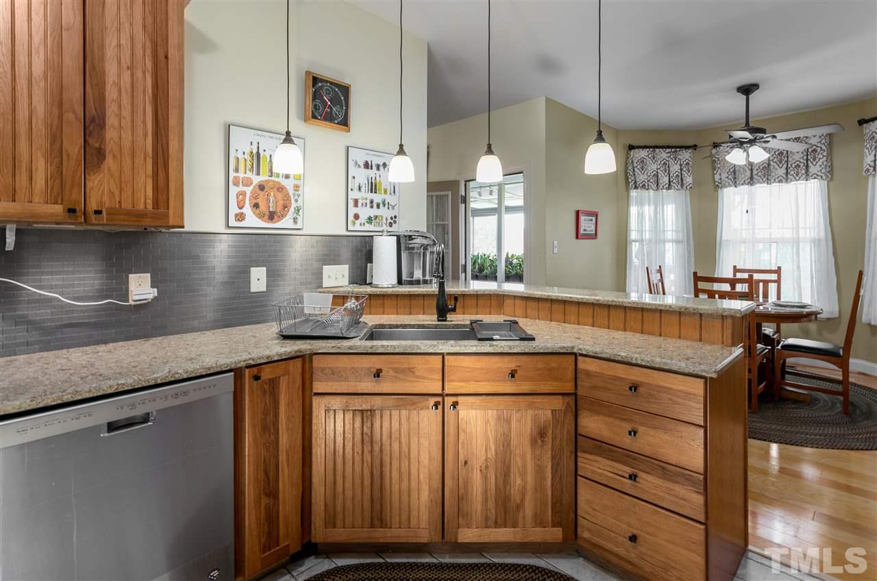 100 North Sunset Ridge Drive Willow Spring, NC 27592 - Photo 6 of 25 a kitchen with kitchen island granite countertop a sink cabinets and wooden floor