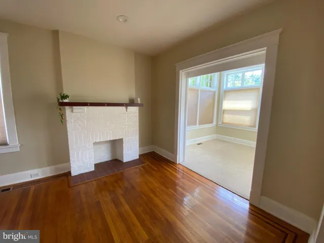 an empty room with wooden floor fireplace and windows