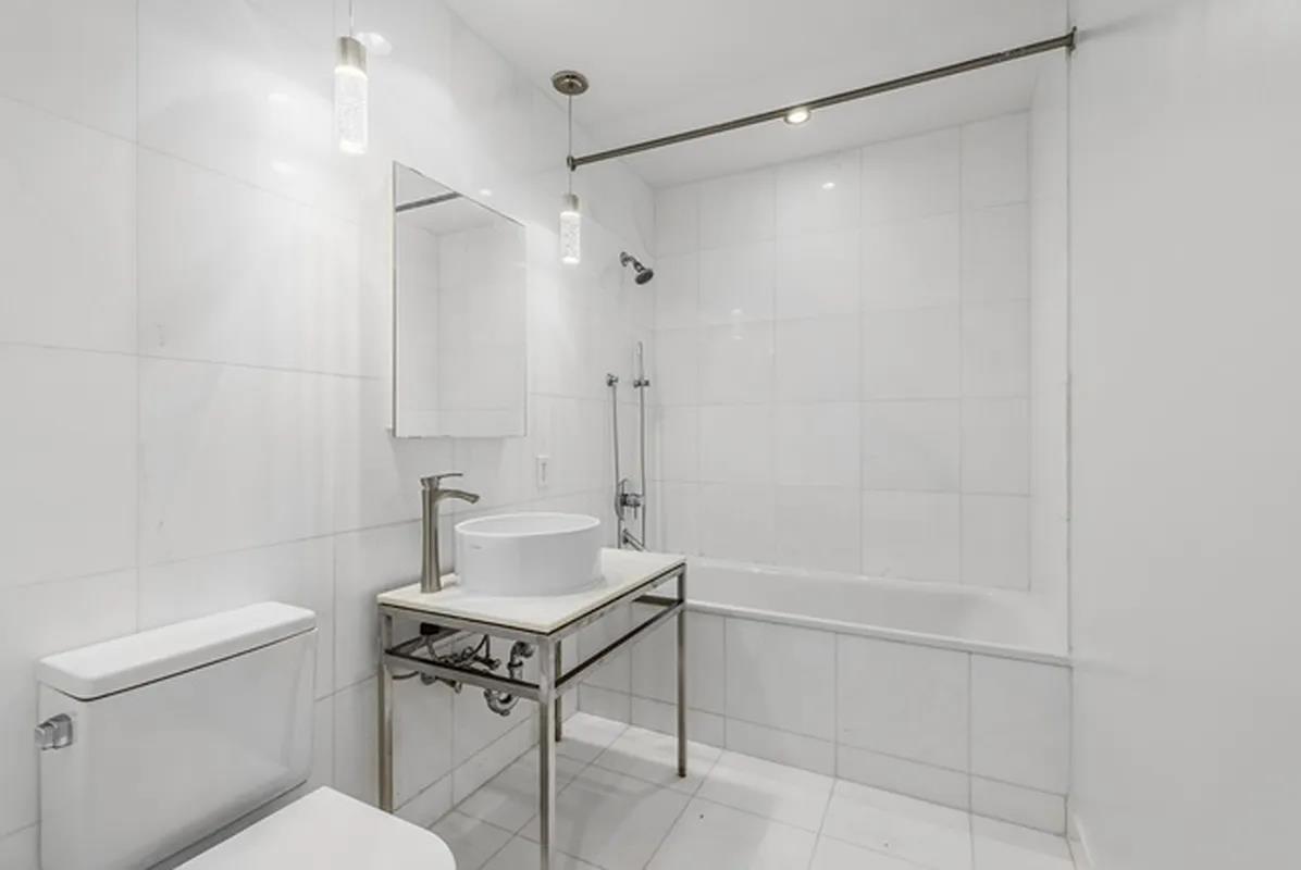 15 Broad Street, Unit 2828 Manhattan, NY 10005 - Photo 4 of 14 a bathroom with a sink a toilet and shower
