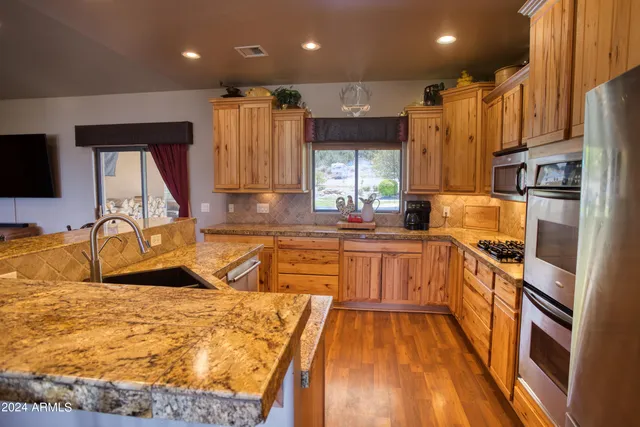 a view of a kitchen with stainless steel appliances granite countertop a sink and cabinets