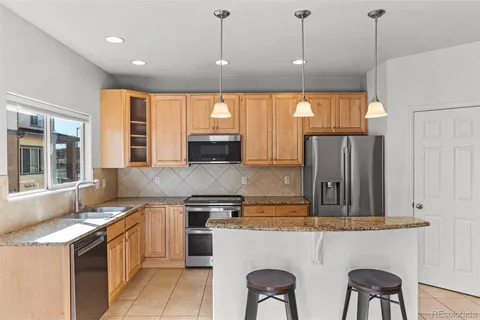 a kitchen with stainless steel appliances granite countertop a stove a sink a refrigerator and chairs