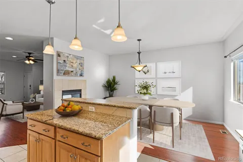 a kitchen with stainless steel appliances granite countertop a refrigerator a stove a microwave oven a dining table and chairs with wooden floor