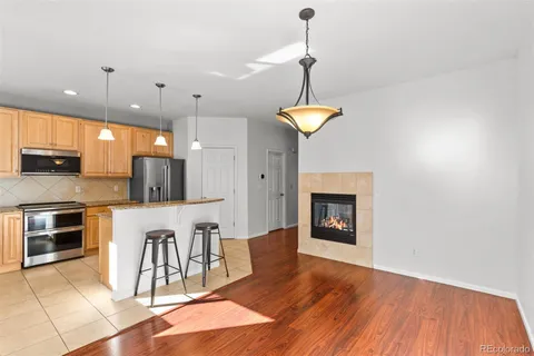 a kitchen with stainless steel appliances granite countertop a refrigerator a stove a microwave oven a dining table and chairs with wooden floor