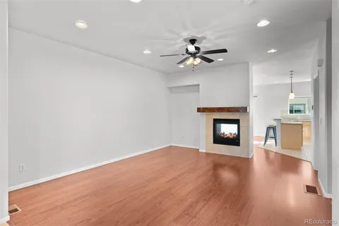 a view of an empty room with wooden floor and a fireplace