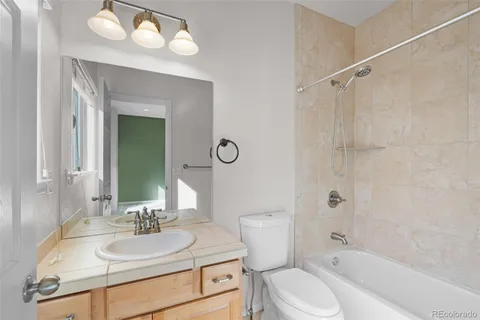 a bathroom with a granite countertop sink toilet mirror and shower