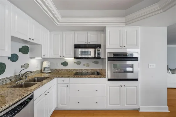 a kitchen with granite countertop white cabinets and stainless steel appliances