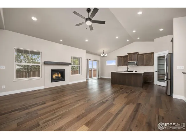 a living room with stainless steel appliances kitchen island a fireplace and wooden floor
