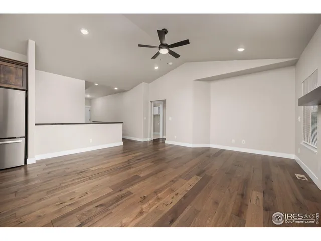 a view of an empty room with wooden floor and a ceiling fan