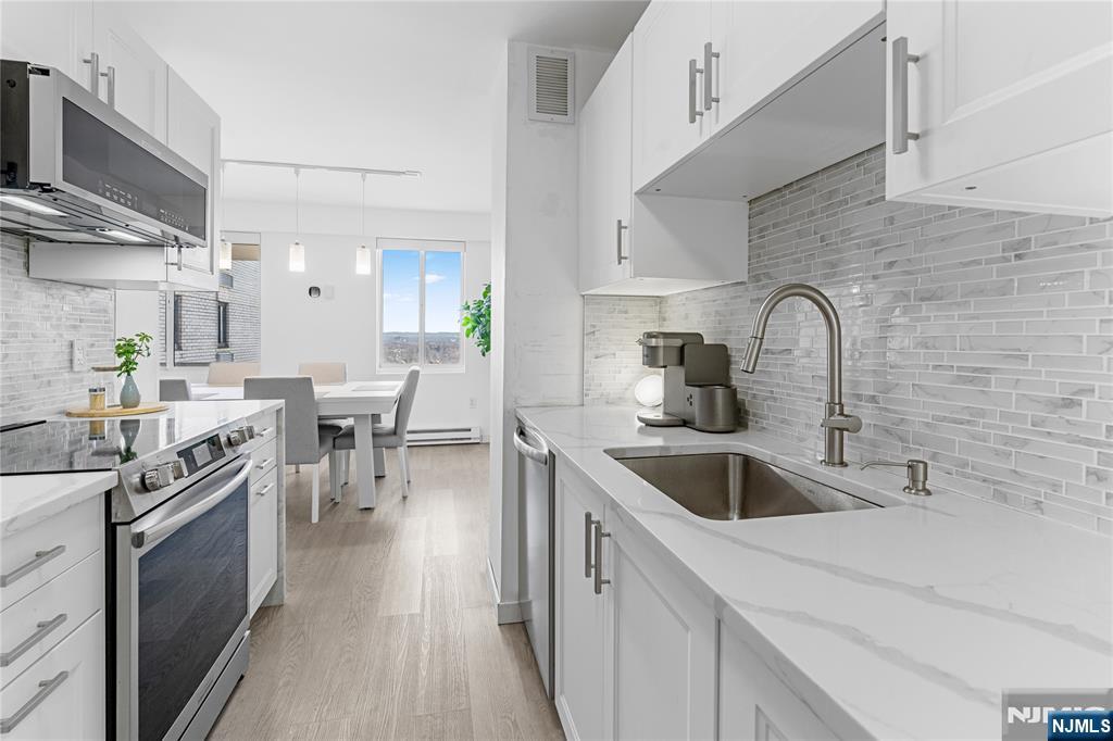 307 Prospect Avenue, Unit 17D Hackensack, NJ 07601 - Photo 7 of 29 a kitchen with stainless steel appliances granite countertop a sink and wooden cabinets
