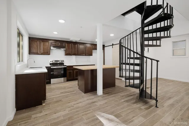 a kitchen with stainless steel appliances kitchen island granite countertop a stove top oven a sink and a refrigerator