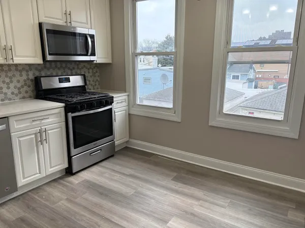 a kitchen with stainless steel appliances a stove a microwave and white cabinets