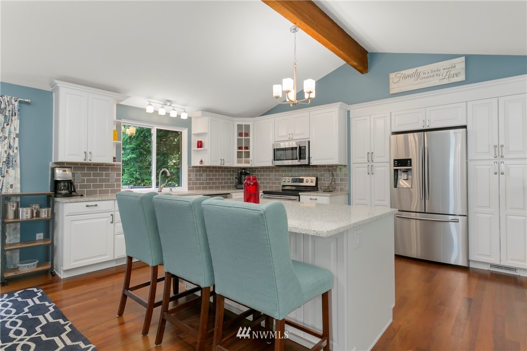 1823 175th Place Southeast Bothell, WA 98012 - Photo 8 of 24 a kitchen with stainless steel appliances granite countertop a refrigerator a stove top oven a sink dishwasher and white cabinets with wooden floor