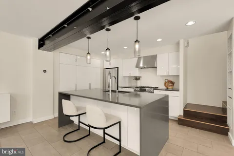 a kitchen with stainless steel appliances kitchen island granite countertop a table chairs and a refrigerator