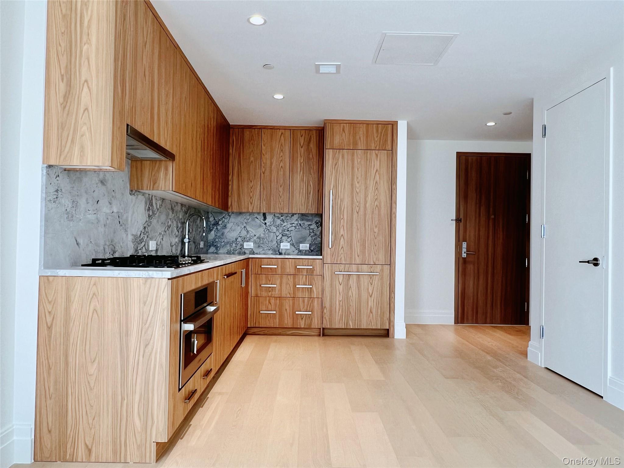 30-55 Vernon Boulevard, Unit 6G Queens, NY 11102 - Photo 8 of 16 a kitchen with granite countertop white cabinets and white appliances