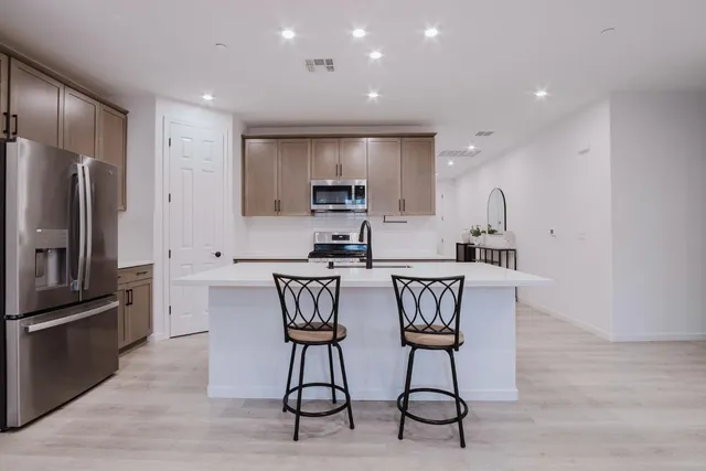 a kitchen with stainless steel appliances a refrigerator a stove a sink a dining table and chairs