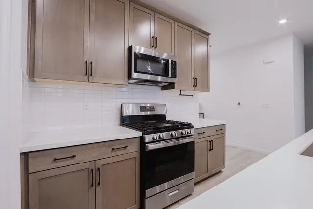 a kitchen with stainless steel appliances granite countertop a stove a microwave and white cabinets