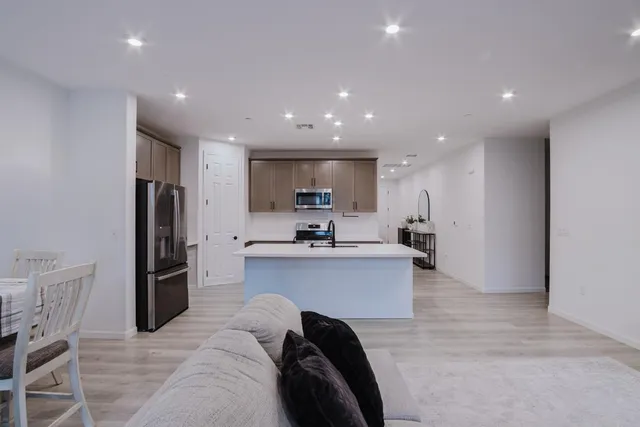 a kitchen with stainless steel appliances kitchen island granite countertop a refrigerator and a sink