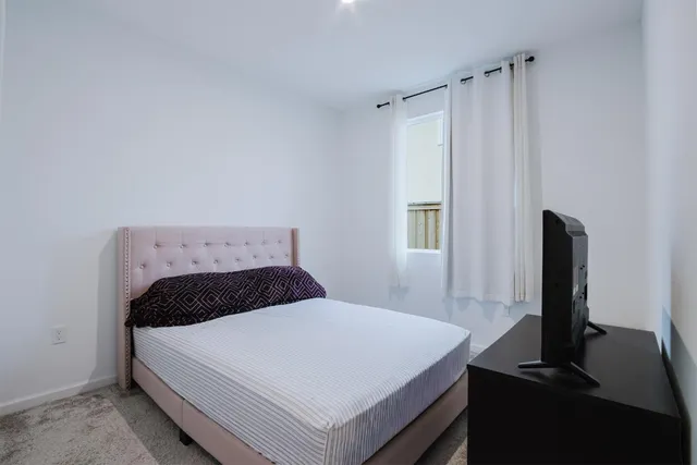 a bedroom with a bed and a flat tv screen on a table