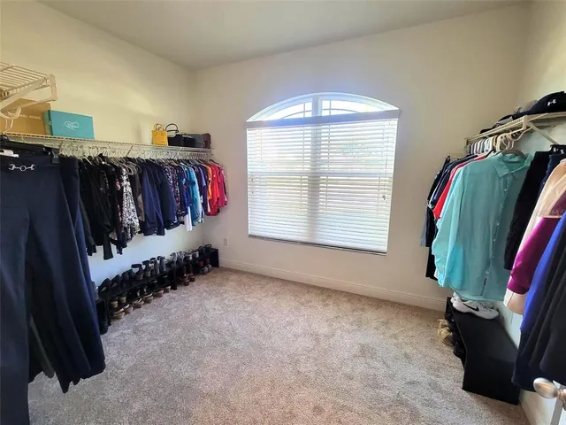 a view of a closet with clothes and shoes