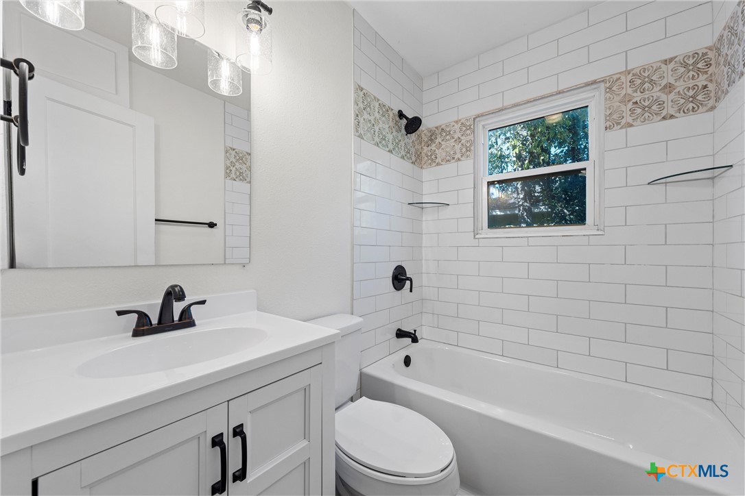 1203 South 5th Street Temple, TX 76504 - Photo 21 of 29 a bathroom with a sink a toilet a mirror a bathtub and shower