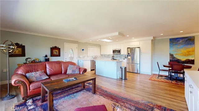 a living room with furniture and kitchen view with wooden floor