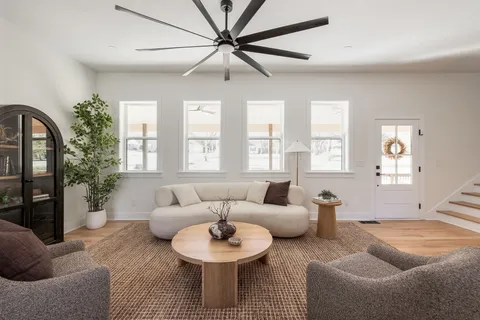 a kitchen with kitchen island a stove a sink dishwasher a refrigerator and white cabinets with wooden floor