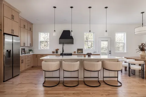 a kitchen with stainless steel appliances granite countertop a stove a sink a dining table and chairs with wooden floor